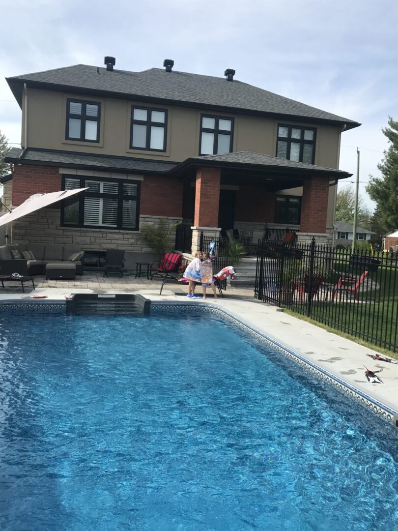 A pool with people sitting in it and a house