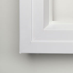 A close up of the door frame on a white cabinet.