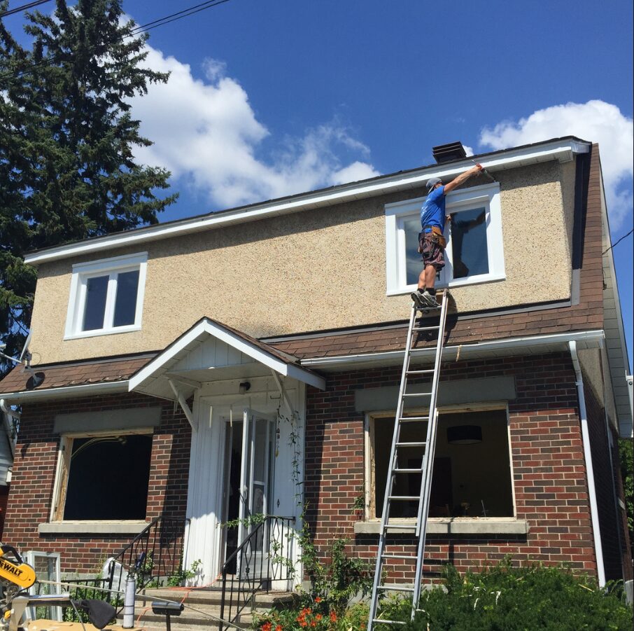 A man on a ladder, installing a window