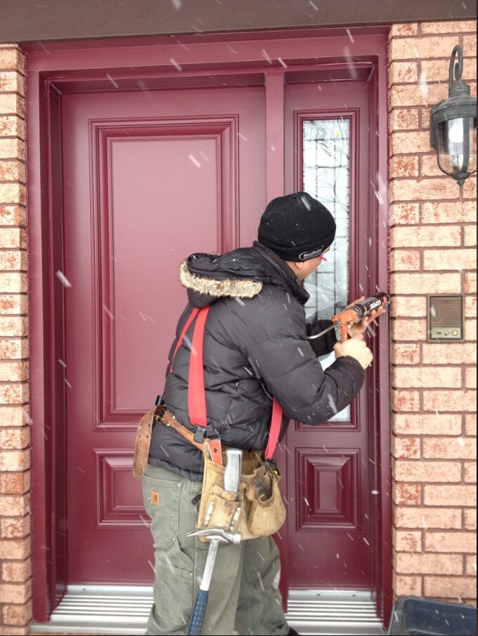 A man installing a red entry door