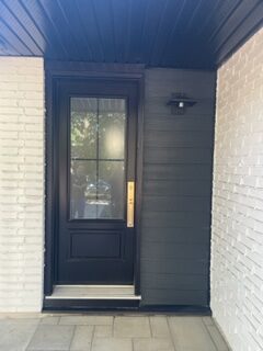 A black door with a glass window and a light on the outside.