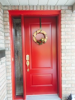 A red door with a wreath hanging on the side.