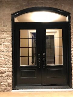 A black door with two windows and a light on the outside.