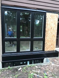 A black window frame with wood paneling on the outside.