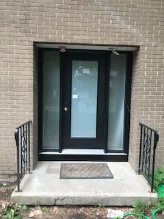 A door with glass and metal steps leading to it.