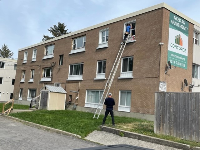 A man standing on the side of a building next to a ladder.