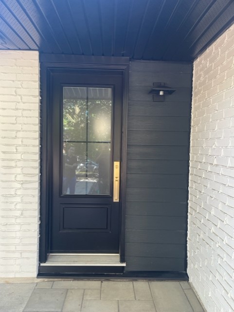 A black door with a white brick wall