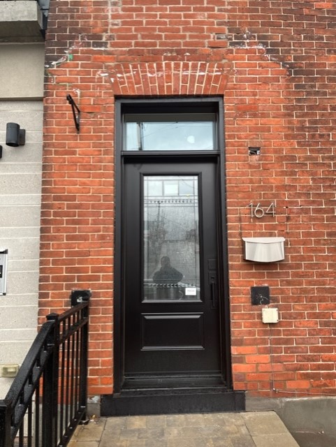 A black door and window on the side of a brick building.